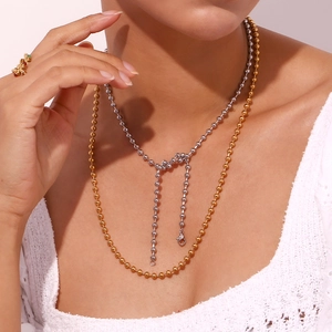 Detail of multi-layered 18K gold and silver beaded necklaces on a model neck