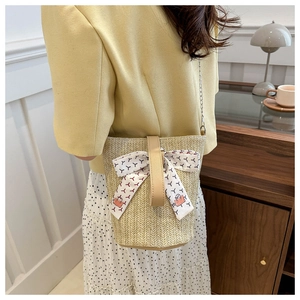 Détail d'un sac cabas en paille beige avec foulard en soie et bandoulière en chaîne