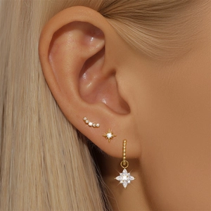 Close-up of a s925 silver earring set with golden star studs and zircon hoops on ear