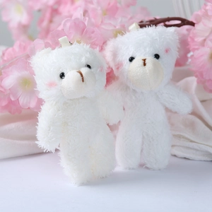 Close-up of plush white teddy bear charms with cute pink blush and silk hanging ribbons