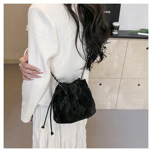 Detail of a black drawstring bucket bag with leather chain strap and metallic texture