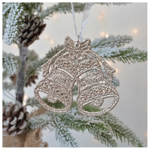 Close-up of champagne gold glitter bells with bow on a festive snowy Christmas tree