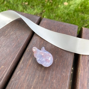 Barrette à cheveux marbrée rose avec strass et perles posée sur un banc en bois
