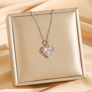 Pink heart crystal necklace with colorful zircons on a gold jewelry box with silk background