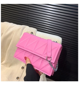 Detail of hot pink quilted crossbody bag with geometric patterns and silver chain