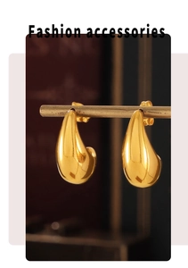 Macro detail of tear-drop gold earrings hanging on a metal bar with high-gloss finish
