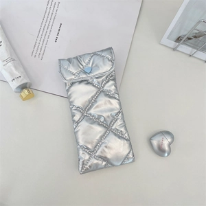 Detail of silver quilted PU leather glasses pouch with a blue heart button closure