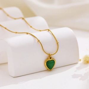 Elegant gold-plated stainless steel necklace with green heart pendant on white stand