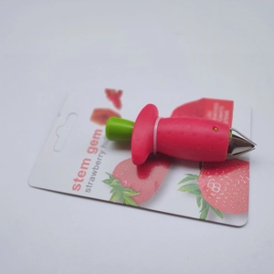 Close-up of strawberry huller tool with metal claws in creative red fruit packaging