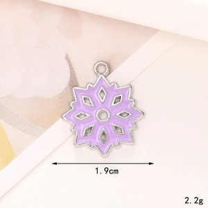 Detailed close-up of a silver-toned snowflake pendant with purple enamel, 1.9cm width