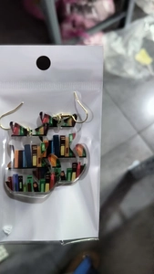 Detail shot of cat-shaped acrylic earrings with colorful bookshelf pattern for teachers