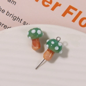 Close-up of green glass mushroom charms with white polka dots for DIY jewelry making