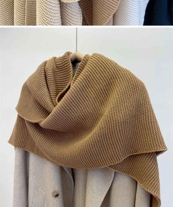 Detailed texture of camel knit shawl draped over a beige wool coat on a wooden hanger