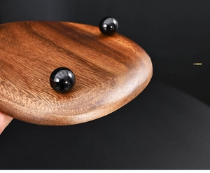 Macro shot of walnut wood tray with black lacquered spherical feet and natural grain