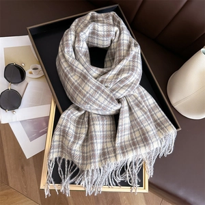 Detail of beige and brown plaid cashmere-like scarf with fringe texture on a black tray