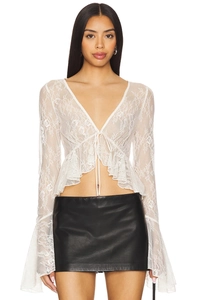 Dettaglio top in pizzo bianco con scollo a V e maniche a campana con bordo a balze