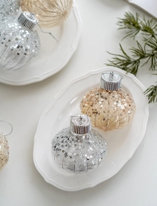 Detail of glitter pumpkin-shaped Christmas ornaments in champagne and silver on a plate
