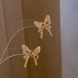 Detailed shot of bow-shaped stud earrings with pink and green pavé zircons in gold
