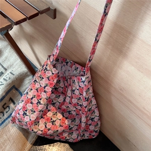 Close-up of vintage floral canvas tote bag with red and pink rose print on rustic background