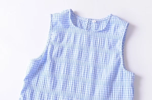 Detail of blue gingham sleeveless top with textured ruched fabric and round neckline