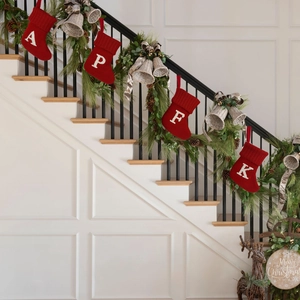 Close-up of red knitted Christmas stockings with letters hanging on decorated staircase