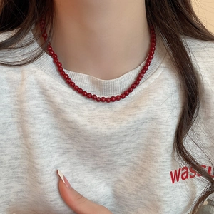 Detail view of the red glass beaded necklace worn as a minimalist collar bone chain