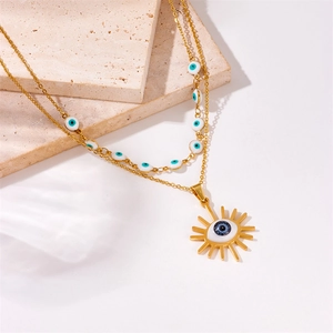 Detail of double-layer gold necklace with blue evil eye beads and sun pendant
