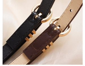Detailed view of elegant black and brown leather belts with gold buckles on silk