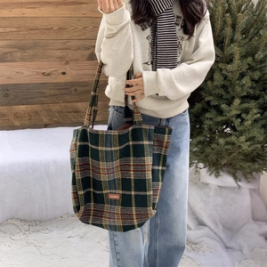 Détail du grand sac cabas en laine à carreaux avec étiquette cuir en décor d'hiver