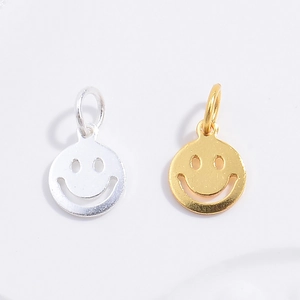 Macro shot of silver and gold smiley face charms with polished metal finish and loops