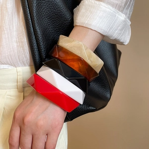 Stack of five geometric resin bangles in marble, amber, black, white, and red finishes