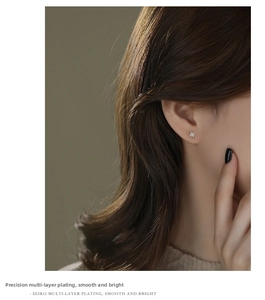Detail view of dainty silver star stud earring with shimmering crystal inlay on model's ear