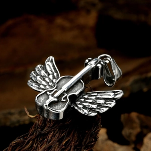 Macro shot of a silver vintage violin pendant with wings on a wooden background