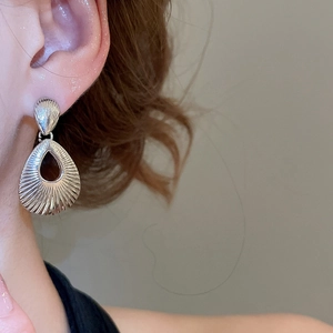 Close-up of silver teardrop earrings with textured vertical ridges worn by a model