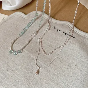 Elegant double-layered silver necklace with teardrop pendant and light blue crystal beads
