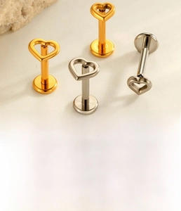 Macro detail of hollow heart titanium labret studs in gold and silver finishes