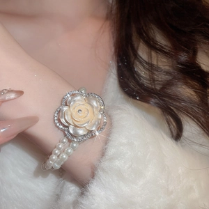 Detailed close-up of double-layer pearl bracelet with rhinestone flower charm on wrist