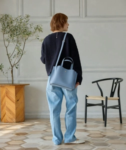 Detail of light blue PU leather crossbody bag worn by a model in a minimalist interior