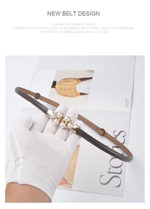 Detail of thin dark grey leather belt with gold pearl buckle and rhinestone accents
