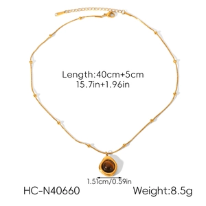 Detail view of a gold snake chain necklace with brown gemstone pendant and size specs