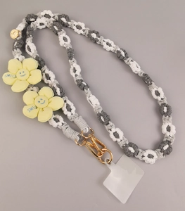 Detail view of hand-woven cotton phone strap with yellow smile flower charms and metal clasp