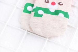 Close-up of beige knitted cotton sock featuring a cute reindeer jacquard pattern