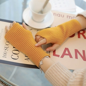 Detail of yellow knitted fingerless gloves with rib texture on a cozy lifestyle background