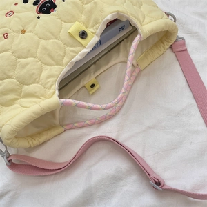 Détail du sac fourre-tout jaune matelassé avec broderie chat et bandoulière rose