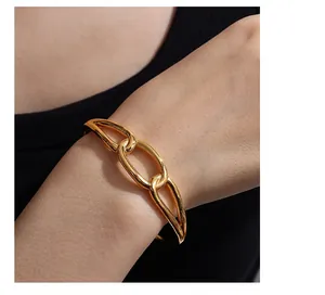 Detail of gold chunky link bracelet featuring three intertwined polished metal rings