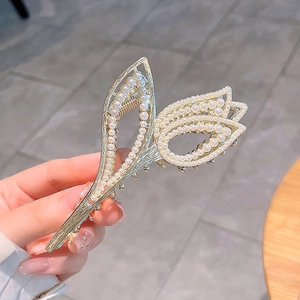 Golden tulip flower hair claw clip with pearls and rhinestones shown in hand