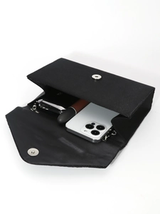 Elegant black evening clutch bag with open flap showing smartphone and lipstick inside