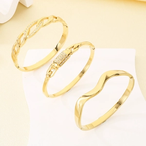 Détail de trois bracelets en acier inoxydable plaqué or 18 carats ornés de zircons brillants