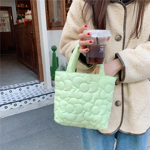 Detailed outdoor shot of light green quilted tote bag with unique 3D floral textures