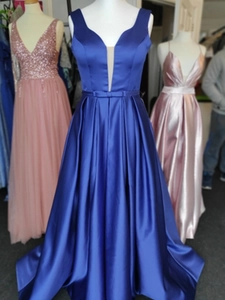 Detail of royal blue satin evening gown featuring deep V-neck and bow waist belt